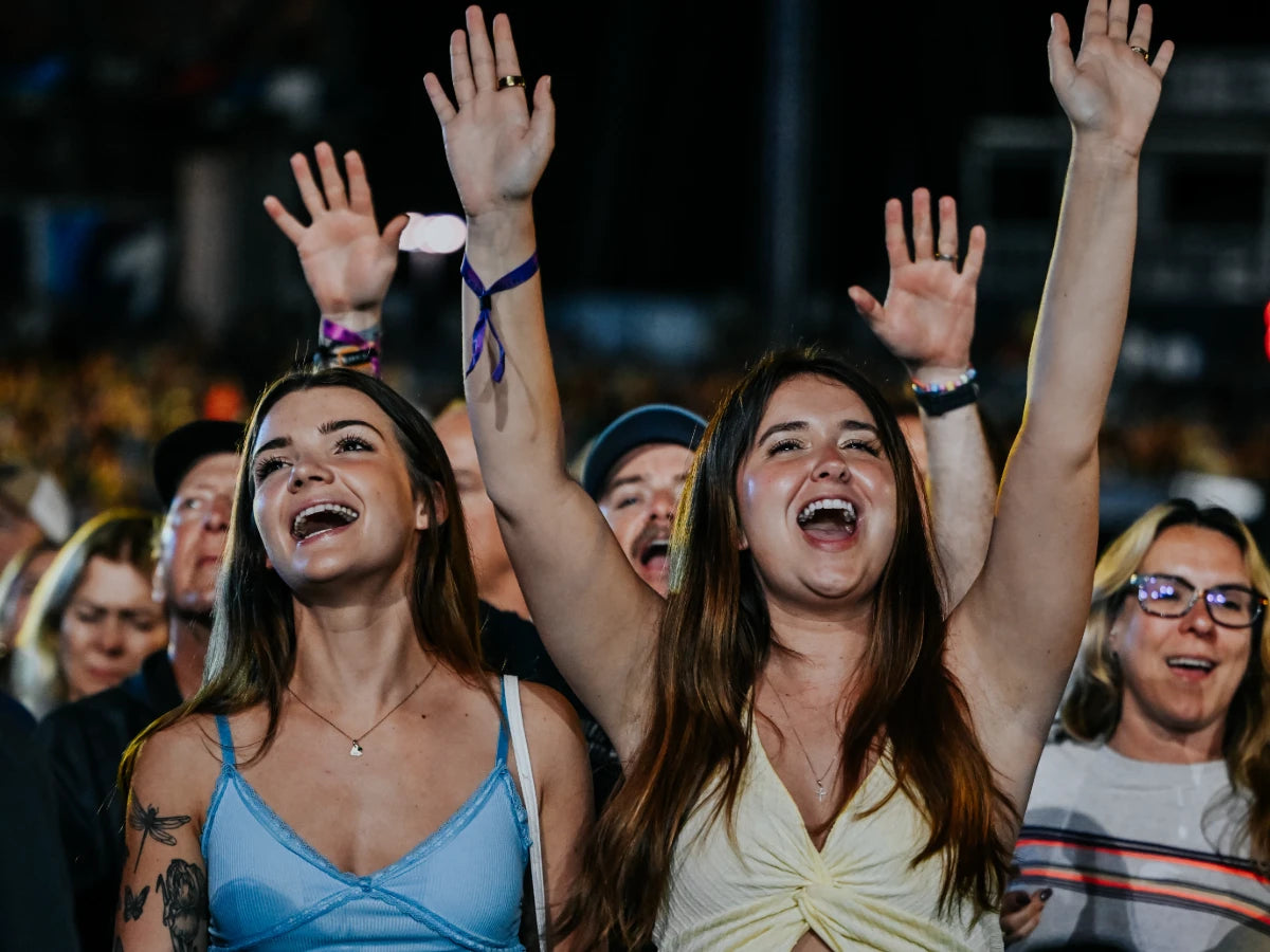 Two girls sing and raise their arms during a concert performance CMA Fest.